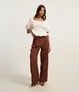 Pantalón pantalona de sastrería color marrón, con pliegues delanteros, cintura con trabillas y corte amplio.