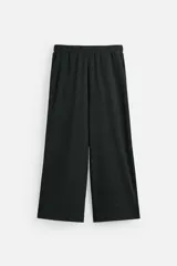 Pantalón negro de corte amplio con cintura elástica ajustable con cordón, bolsillos delanteros y detalle de bolsillo trasero de vivo.