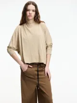 Camiseta beige de manga larga con cuello redondo y corte amplio. El ruedo presenta terminaciones desflecadas.