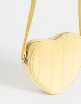 Bandolera negra en forma de corazón, confeccionada en cuerina acolchada con pespuntes verticales. Tiene correa larga regulable y cierre superior.