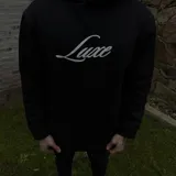 Buzo hoodie negro de corte oversize, con capucha, bolsillo frontal y estampa blanca en la espalda con la leyenda "Luxe" y "The Luxe Vip Club".