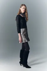 Minifalda plateada de cuero ovino con volado en el ruedo, tachas decorativas y cierre lateral.