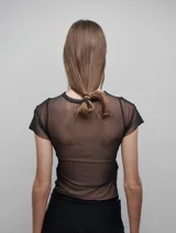 Camiseta negra de corte ajustado, con mangas cortas y espalda de tul transparente. Diseño versátil que permite usarla tanto de frente como de espalda.