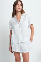 Conjunto de pijama de viscosa color blanco con estampado floral celeste, compuesto por una camisa de manga corta con cuello y botones, y un short con cintura elástica.