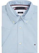Camisa celeste de mangas cortas, confeccionada en popelín de puro algodón. Tiene cuello abotonado, bajo redondeado y logo de Tommy Hilfiger bordado en el pecho.
