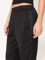 Pantalón negro de sarga, con elástico en la cintura, bolsillos laterales y ojal en la espalda.