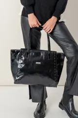 Bolso negro de cuero vacuno con costuras de hilo engrasado en los laterales. Interior de tejido de algodón con dos bolsillos. Aplique metálico de la marca en el frente. Cierre principal y bolsillo trasero con cierre.
