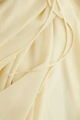 Pollera circular larga color amarillo pálido, de gasa transparente con viso corto. Presenta cintura alta con elástico, tiras finas largas en los laterales y bajo asimétrico con tajo pronunciado en los laterales.