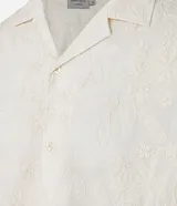 Camisa de manga corta color crema con bordado floral texturizado, cuello solapa y abotonadura frontal.