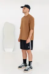 Remera color marrón con efecto gastado, corte holgado, mangas cortas y estampado en la espalda con dos rostros enfrentados y la palabra "Forgive".