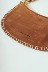 Cartera de hombro negra con forma de media luna, confeccionada en material con textura de pelo o cuero. Presenta costura decorativa gruesa en el borde y correa ajustable con herrajes metálicos plateados.