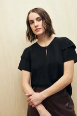 Blusa blanca de tela liviana con mangas cortas con volados y botón de nácar.