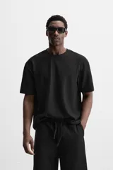 Camiseta negra de corte holgado, con cuello redondo y mangas cortas.