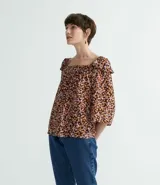 Blusa marrón con estampado de flores pequeñas, escote cuadrado, mangas 3/4 anchas con volantes en los hombros y pliegues en el busto.