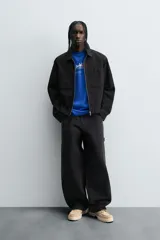 Pantalón negro de corte amplio, confeccionado en tejido de algodón con efecto lavado. Presenta bolsillos frontales, traseros de parche, tira multifunción y bolsillos laterales en las perneras. Cuenta con cierre frontal con cremallera y botón.