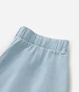 Pantalón tipo pantacourt de jeans en tono delavê, con corte amplio y largo a media pantorrilla. Presenta cintura con elástico en la espalda, cierre frontal con botón forrado, bolsillos laterales tipo cuchillo y pliegues delanteros.