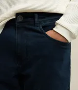 Pantalón de jean azul oscuro, corte slim, con trabillas en la cintura y bolsillos.
