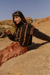 Sweater tejido a mano de algodón con cuello alto y diseño con rayas diagonales en color naranja y detalles en cuero natural.