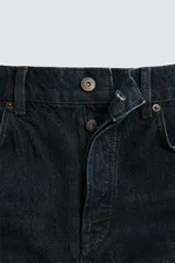 Jeans azul oscuro de corte recto, con largo al tobillo, confeccionados en denim de algodón con efecto lavado. Diseño de cinco bolsillos y cierre frontal con botones.