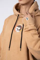 Buzo canguro color ocre con capucha y cordones negros, de corte oversize y confeccionado en tela de algodón friza con teñido artesanal y estampa circular en el pecho.