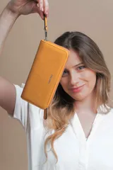 Billetera larga color mostaza de símil cuero, con cierre alrededor y bolsillo trasero con cierre.