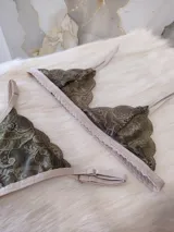 Conjunto de lencería de encaje verde musgo con detalles en beige, compuesto por un corpiño triangular sin aro y una tanga con tiras ajustables.