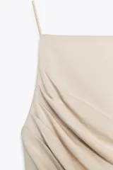 Top halter color beige con tirantes finos y detalle de frunces en el lateral.