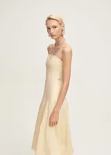 Vestido midi color crema, de lino, con escote strapless y falda con bajo abullonado.