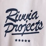 Remera blanca de manga corta con estampa centrada en el pecho con el texto "Rivvia Projects" en azul y cinco estrellas debajo.