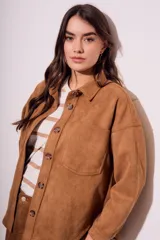 Sobrecamisa negra de gamuza vegana con calce oversize, cuello camisero, cierre con botones a presión, mangas largas con puños abotonados y bolsillos de parche en el pecho.