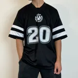 Remera negra estilo fútbol americano con cuello en V y mangas cortas con tres rayas blancas. Estampado frontal con logo y número 20 en blanco.
