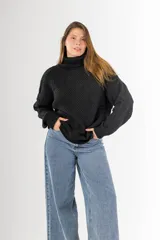 Sweater negro tejido en punto arroz, con cuello alto, mangas largas y silueta holgada.