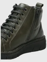 Botín de cuero color verde oscuro con sistema de ajuste mediante cordones negros y suela de poliuretano flexible. Presenta una caña de 10 cm y un taco de 3 cm, ofreciendo un diseño ergonómico y confortable para el uso diario.