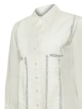 Blusa color crema con cuello camisero, mangas largas y detalles de encaje en el frente.