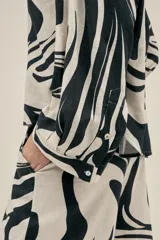 Pantalón ancho con estampado abstracto en blanco y negro, con pinzas en el frente, bolsillos laterales y elástico en la cintura.