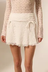 Minifalda blanca de poliéster con cintura alta y cordones laterales.