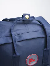 Mochila negra de poliéster con revestimiento de PU, con dos asas de mano y correas ajustables para los hombros. Tiene un compartimento principal con cierre, un bolsillo frontal con cierre y dos bolsillos laterales abiertos.