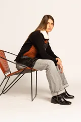 Campera negra con paneles de cuero color marrón, mangas largas de tejido de punto y cuello de piel sintética color crema.
