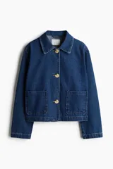 Campera azul de denim con cuello clásico, cierre frontal con botones a tono, mangas largas y bolsillos de parche delanteros.