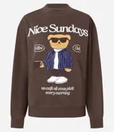 Buzo de algodón y felpa color marrón oscuro con cuello redondo y mangas largas. Presenta un estampado frontal de un oso con gafas de sol y traje a rayas, con el texto "Nice Sundays" en la parte superior y la frase "un café si vous plait morning" en la parte inferior.