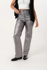 Pantalón plateado de tiro alto confeccionado en gabardina stretch metalizada, con bolsillos y cierre frontal con cremallera y botón.