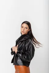 Chaqueta bomber de cuero color marrón, con cuello alto, cierre frontal con cremallera, mangas largas y corte a la cintura. El cuero tiene un acabado rústico con imperfecciones naturales.