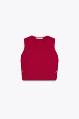 Top chaleco de punto color fucsia, con cuello redondo y sisas amplias. Presenta botones dorados decorativos en los laterales.