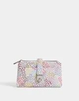 Billetera con formato de fichero, con estampado de corazones multicolores. Tiene doble compartimento con cierre superior y bolsillo frontal con lazo y broche metálico. Cuenta con compartimentos para tarjetas y billetes.