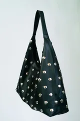 Bolso negro tipo hobo de cuero sintético con apliques de tachas plateadas.