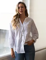 Blusa blanca de algodón bordado, marca Hetser & Orchard. Cuello a la base, escote en V y abertura central con botones. Manga larga amplia.