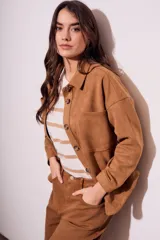 Sobrecamisa negra de gamuza vegana con calce oversize, cuello camisero, cierre con botones a presión, mangas largas con puños abotonados y bolsillos de parche en el pecho.