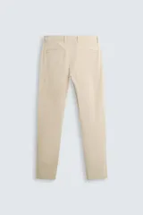 Pantalón chino color beige, corte skinny fit, confeccionado en tejido con mezcla de algodón y elasticidad. Cuenta con bolsillos frontales y traseros. Cierre frontal con cremallera y botón.