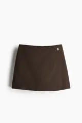 Short pollera marrón con corte mini, de tiro alto, con cierre lateral oculto y bolsillo decorativo trasero.