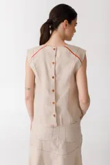 Blusa color ladrillo de lino 100% con cuello redondo y sin mangas. Presenta vivos y pespuntes a contratono en color marrón.